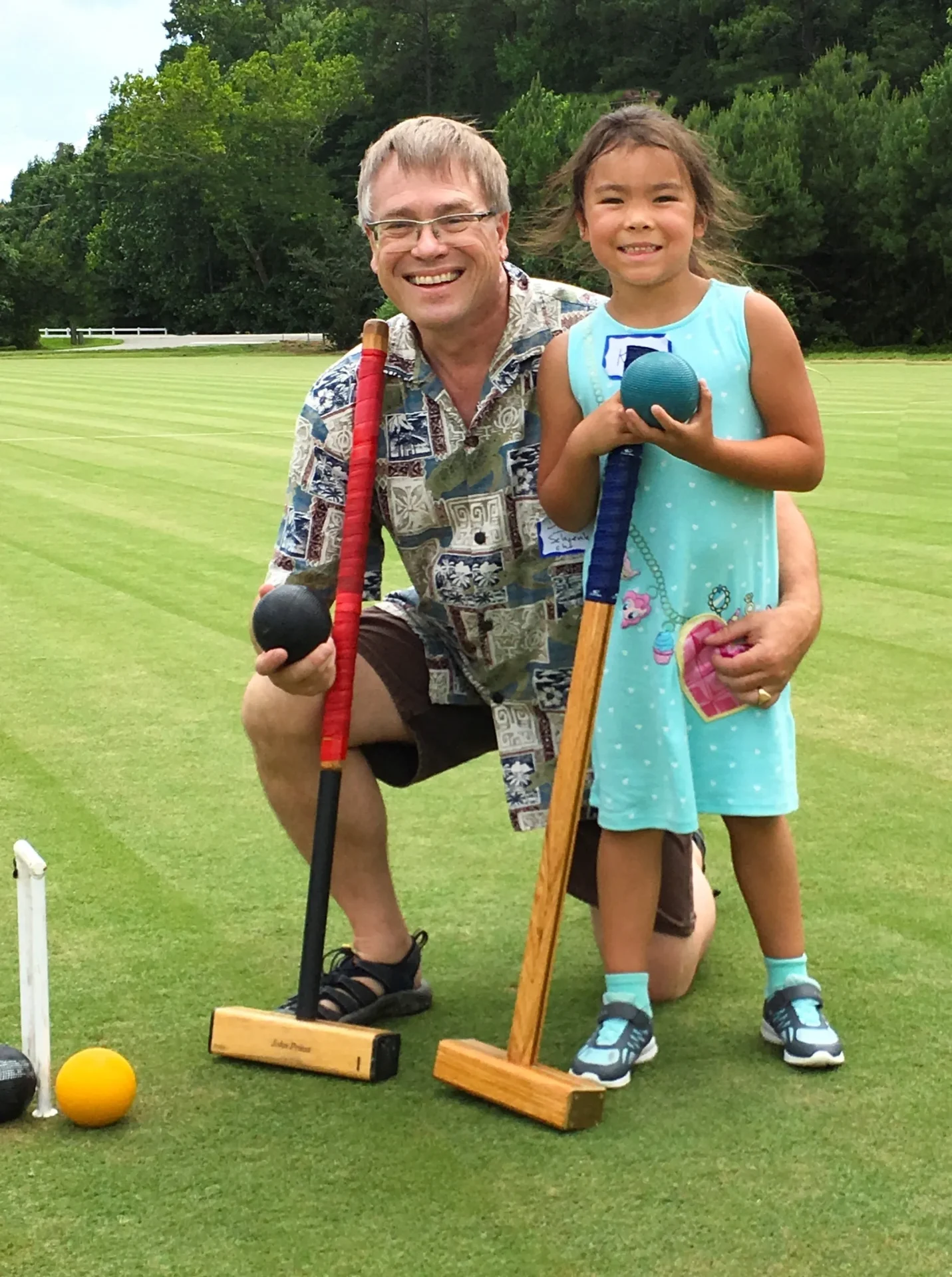 A man and girl are playing croquet on the grass.